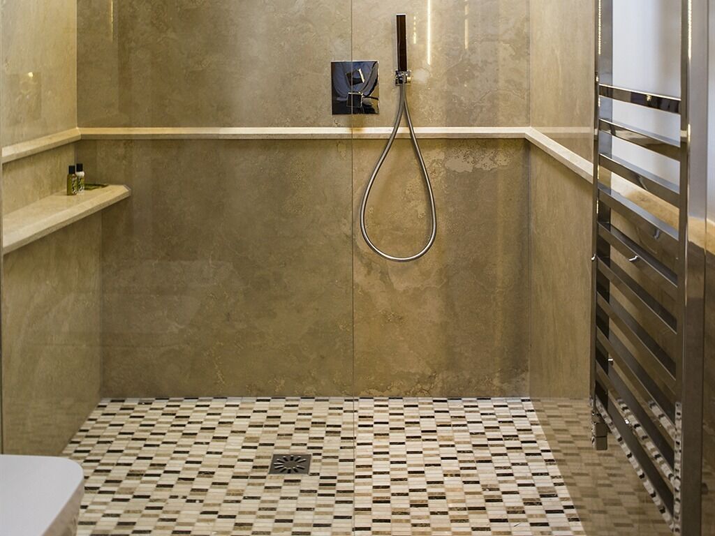 Une salle de bain avec une douche, un carrelage au sol et un porte-serviettes.