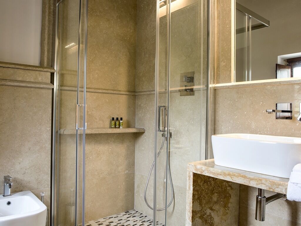 A modern bathroom with a glass-enclosed shower, a white sink, and a marble countertop.