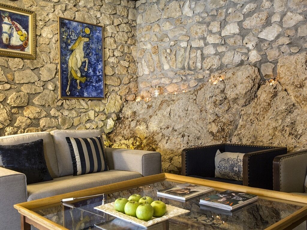Un muro in pietra, un divano, un tavolino con delle mele e opere d'arte incorniciate.