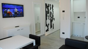 A modern office space with a flat-screen TV, white cabinets, black chairs, and abstract wall art. - LHP Suite Rapallo (Rapallo)