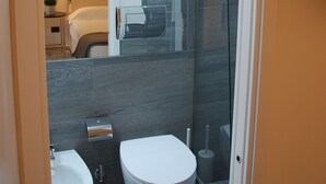 A modern bathroom with a glass shower enclosure, a white toilet, and a sink. - LHP Suite Rapallo (Rapallo)
