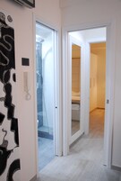 Un pasillo de hotel con un baño, un dormitorio y una zona de ducha.
