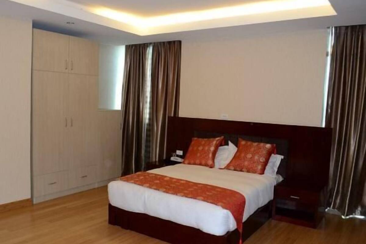 A hotel room with a large bed, a wardrobe, and a nightstand.