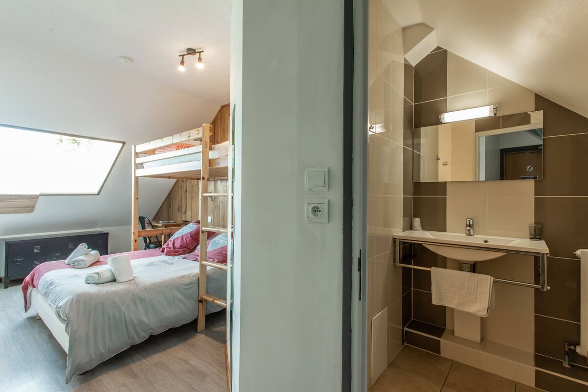 A modern bedroom with a bunk bed, a desk, and a large window.