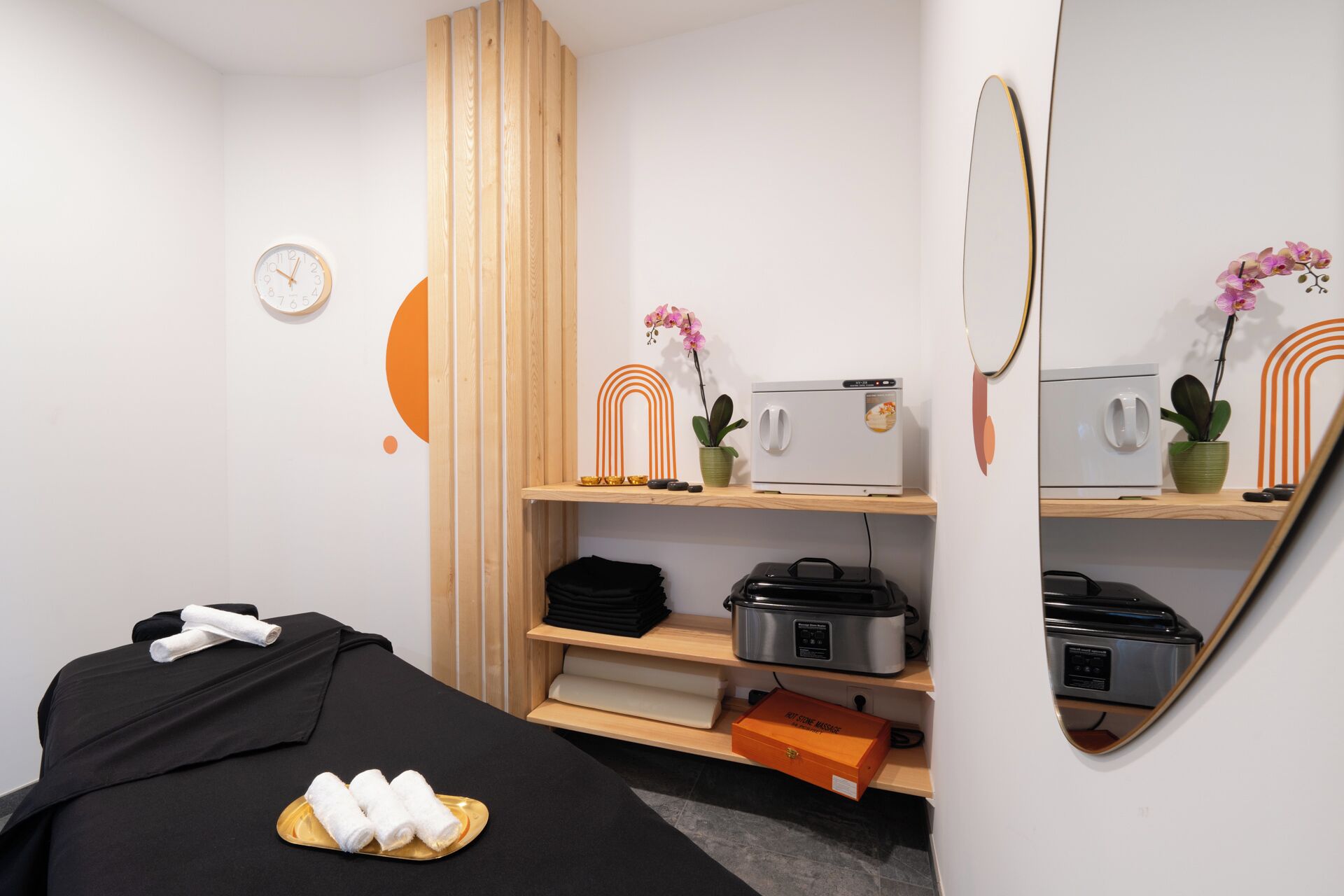 A hotel room with a bed, a small table with towels, a microwave, a coffee maker, and a shelf with decorative items.