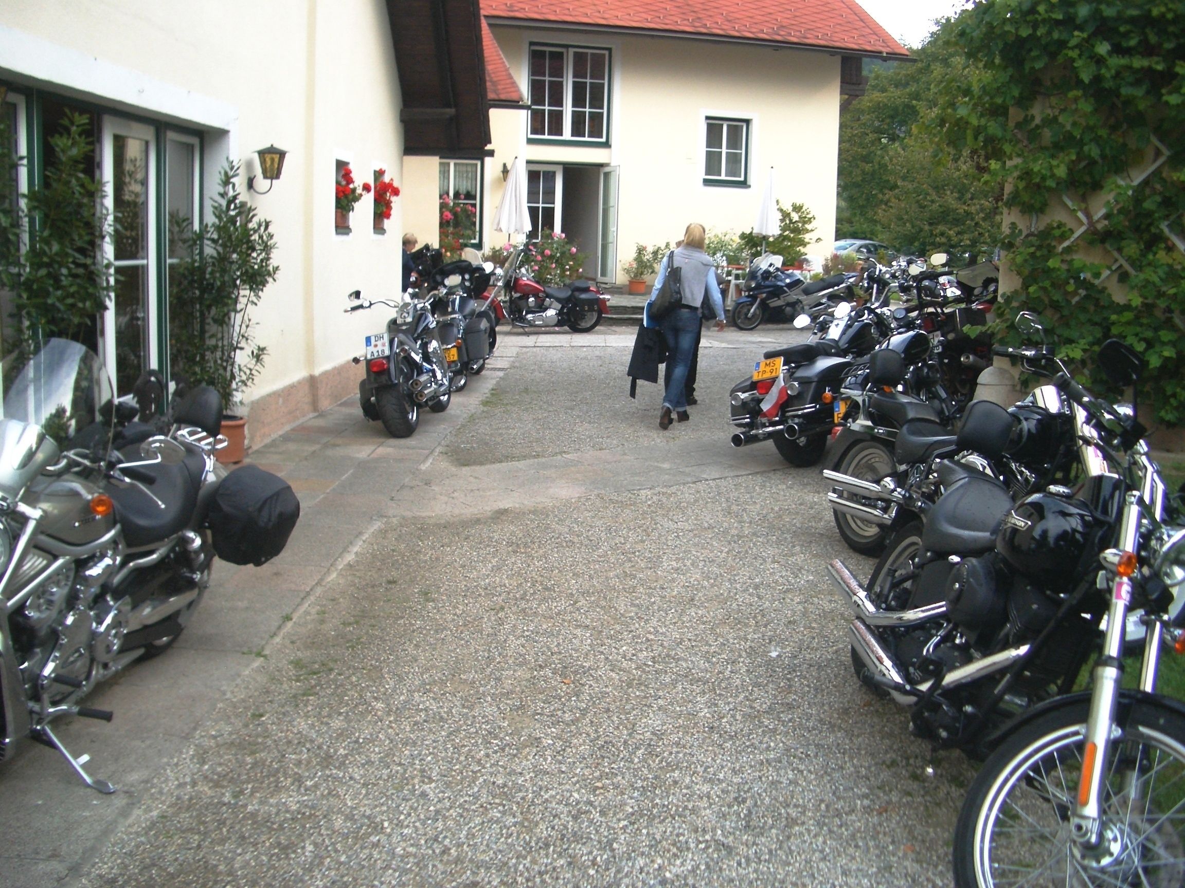 Une allée pavée mène à un bâtiment devant lequel sont garées plusieurs motos.