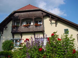 A traditional chalet with a wooden balcony, flower boxes, and a well-maintained garden. - Landhaus Strussnighof (Poertschach am Woerthersee)