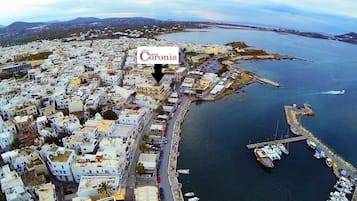 Vista aérea de un pueblo costero con un hotel destacado llamado "Hotel Coronis", señalado con una flecha.