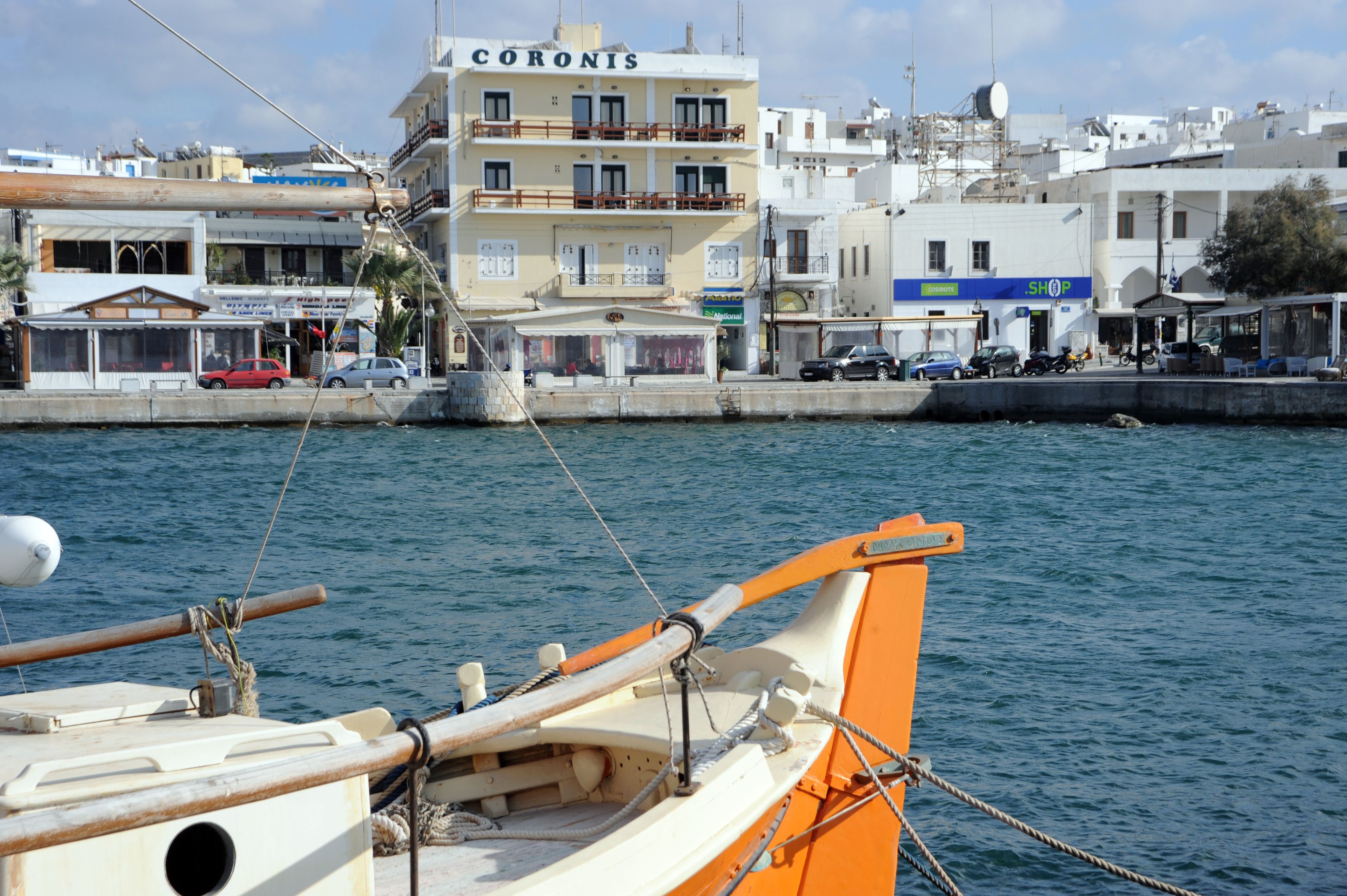 A waterfront building named "CORONIS" with balconies and a shop sign.