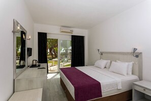 A hotel room with a bed, a nightstand, a mirror, an air conditioning unit, and a view of the outdoors. - Charm Beach Hotel - All Inclusive (Bodrum)