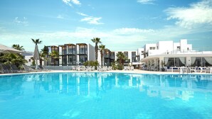 A swimming pool with lounge chairs and a modern building with balconies in the background. - Charm Beach Hotel - All Inclusive (Bodrum)