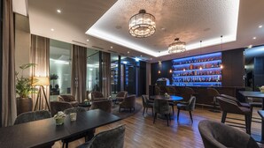 A modern bar area with a wooden floor, leather seating, and a well-lit ceiling with pendant lights. - Hotel Kommod (Ruggell)