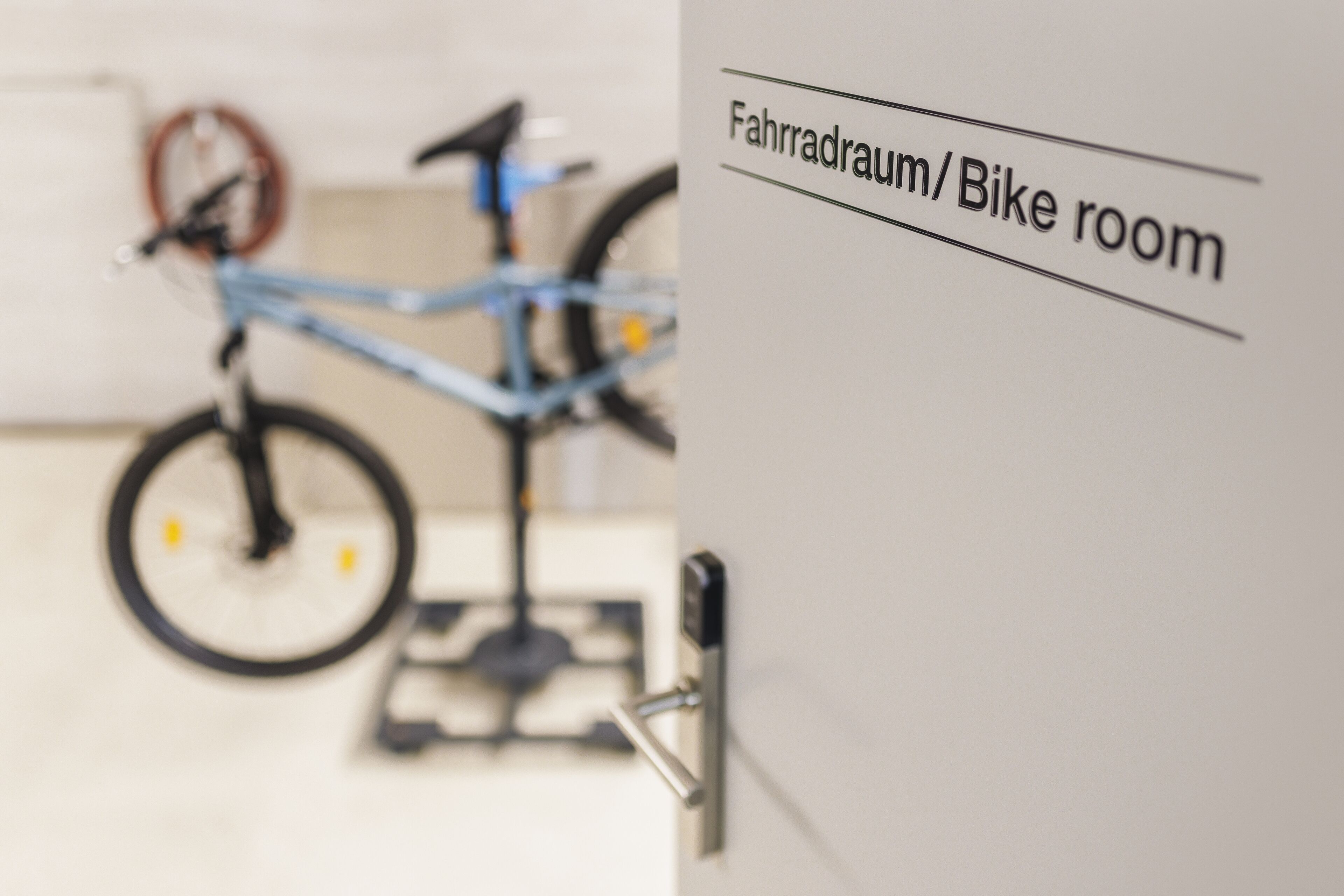 Un cuarto para bicicletas con una bicicleta y una puerta que indica "Fahrradraum/Bike room".