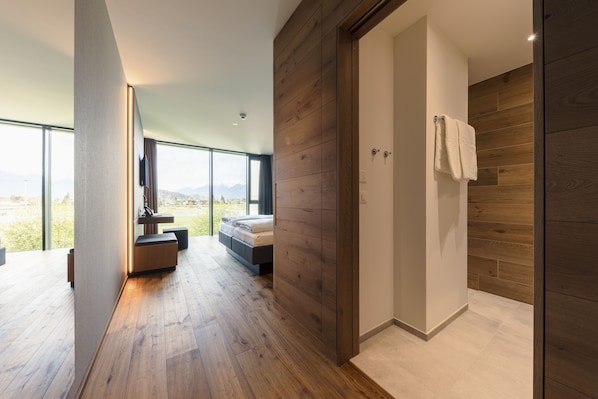 A modern bedroom with a large window, a bed, and a wooden floor.
