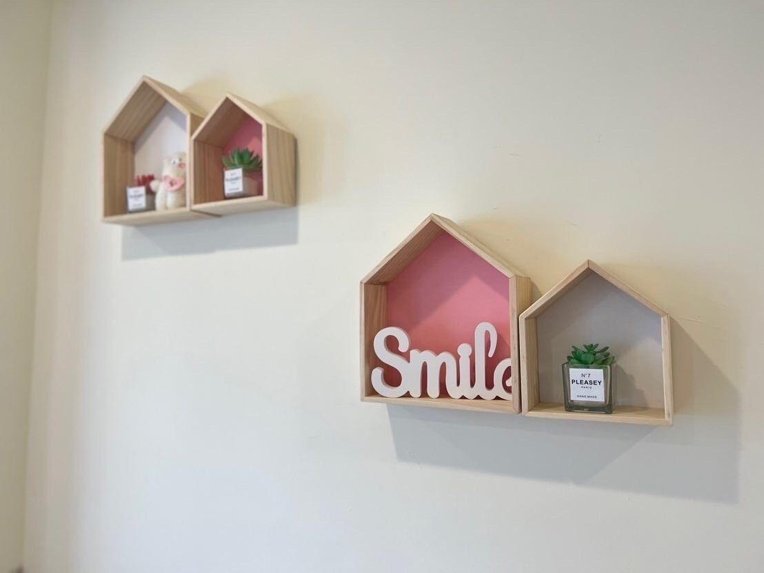 Dos repisas de madera con objetos decorativos, una con un letrero que dice 'Smile' y una planta pequeña.