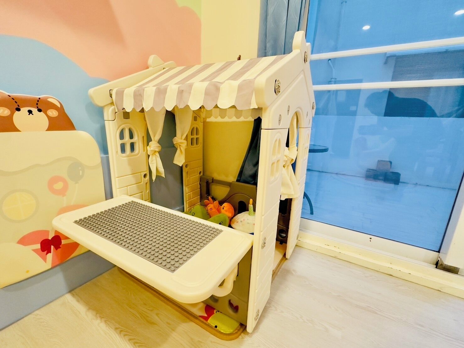 A children's playhouse with a small table and storage drawers.