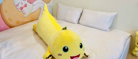 A bed with a yellow plush toy, white pillows, and a wall with a cartoon character.