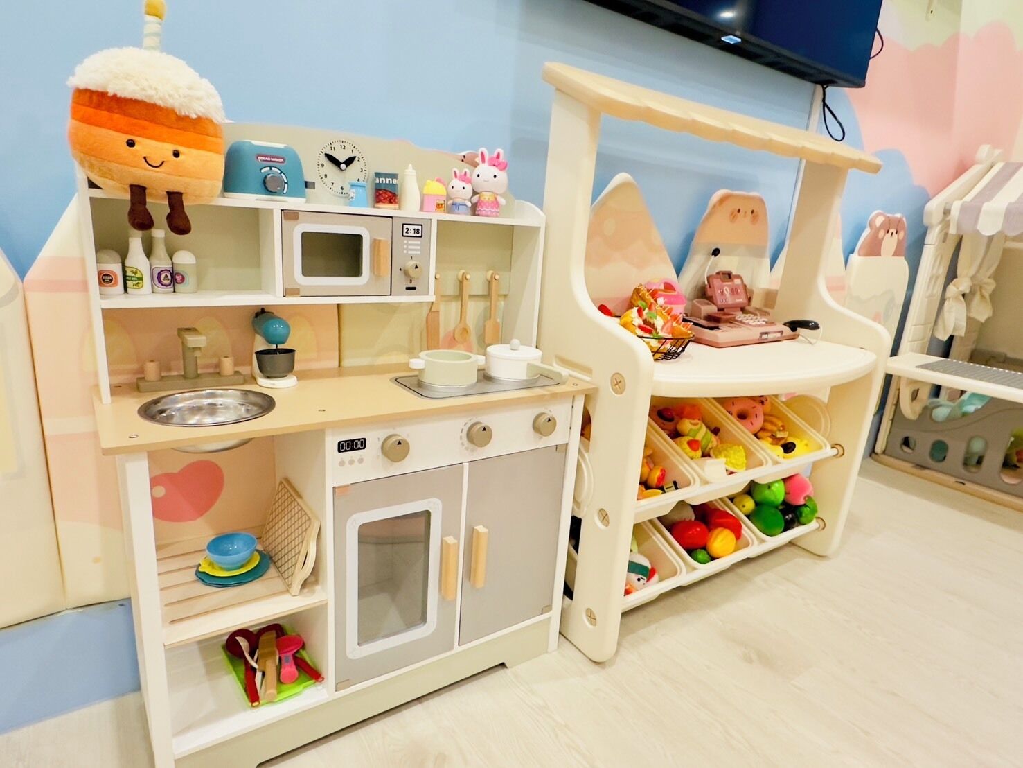 A children's play kitchen with a microwave, oven, and various kitchen utensils.