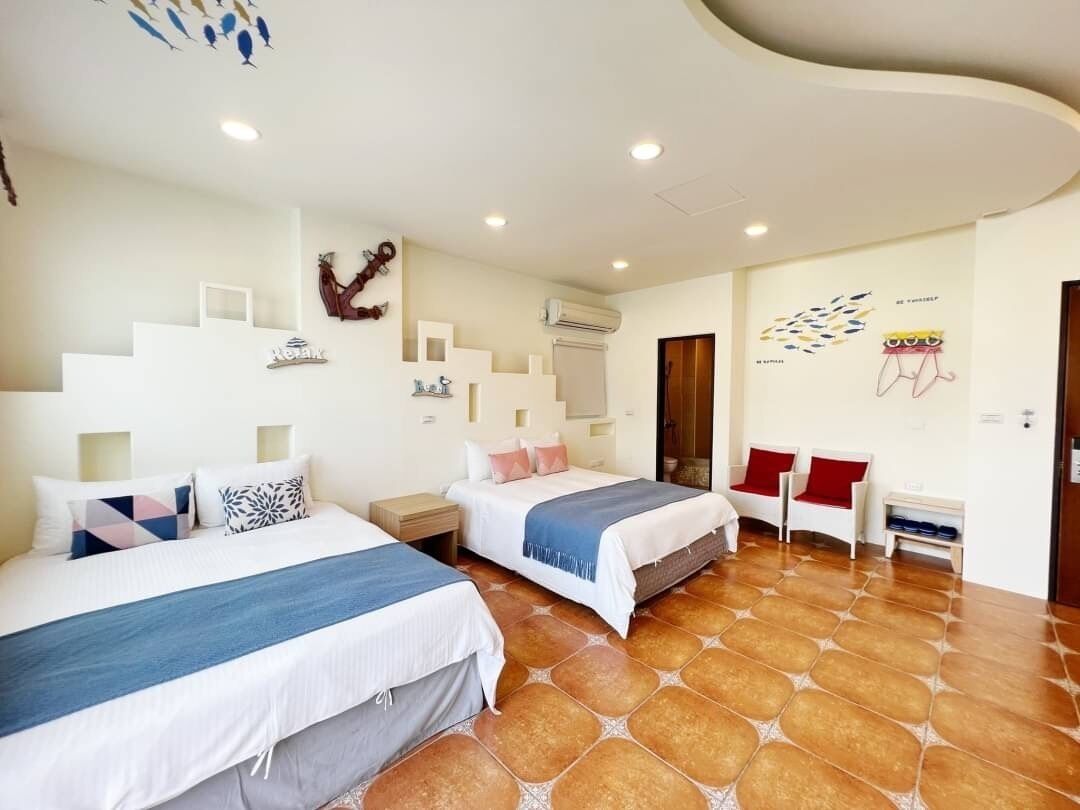 Habitación de hotel con dos camas, un pequeño rincón de descanso y una escalera.