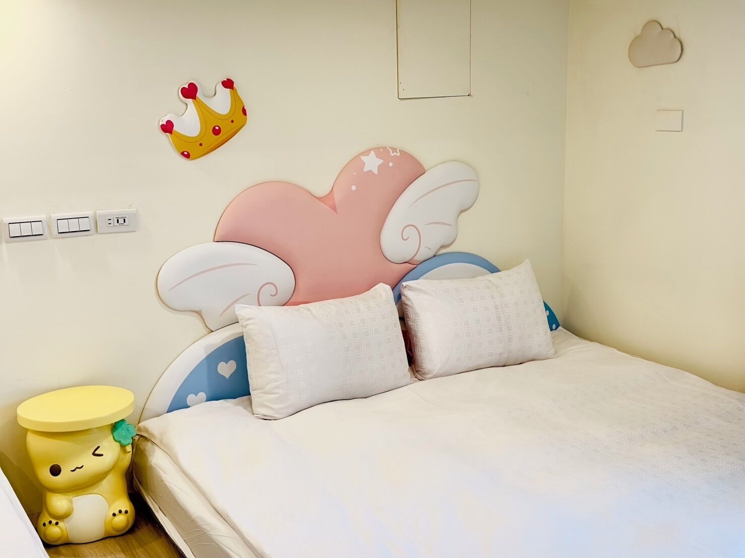 A bedroom with a bed, pillows, a nightstand, and wall decorations.
