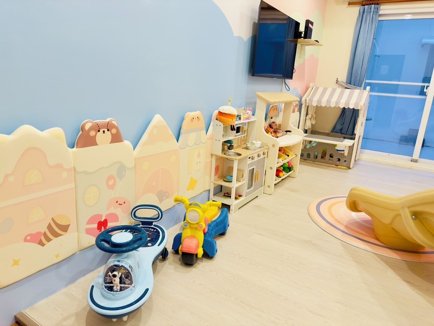 Un área de juegos infantiles con una cocina de juguete, un coche de juguete y una motocicleta de juguete.