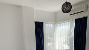 A hotel room with two beds, white bedding, dark blue curtains, and a hanging light fixture. - Lizo Hotel (Kas)