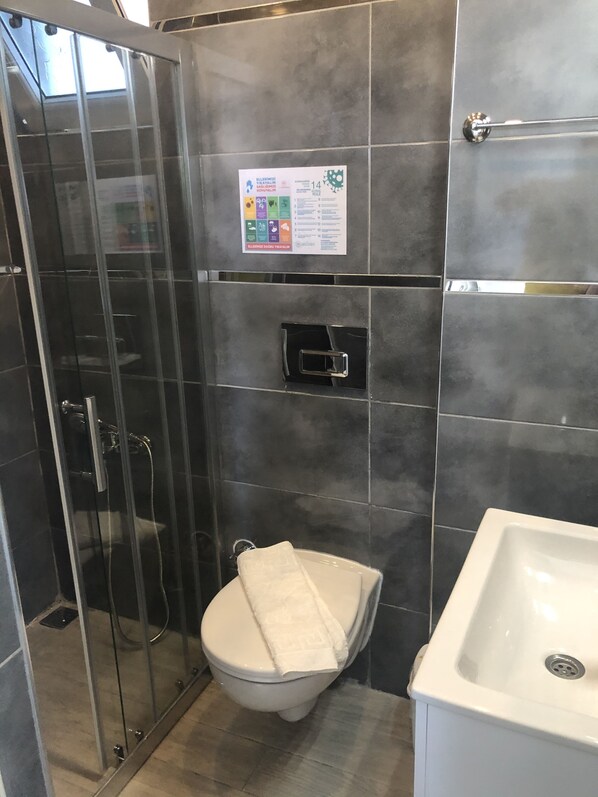 A bathroom with a glass-enclosed shower, a toilet, and a sink.