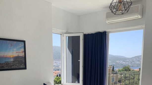 A bedroom with a large bed, a view of the city, and a balcony. - Lizo Hotel (Kas)