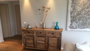 A wooden console table with drawers, a vase with dried flowers, and decorative items on top. - Luxus Ferienapartment “ Im Feldle „ (Kirchheim am Ries)