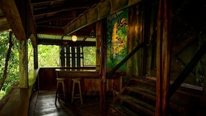 Un coin bar rustique en bois, avec un banc et des tabourets en bois, un escalier et une fresque murale.