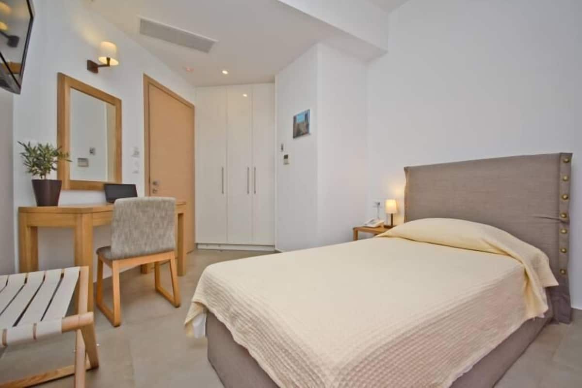 A bedroom with a bed, a desk, a chair, and a wardrobe.