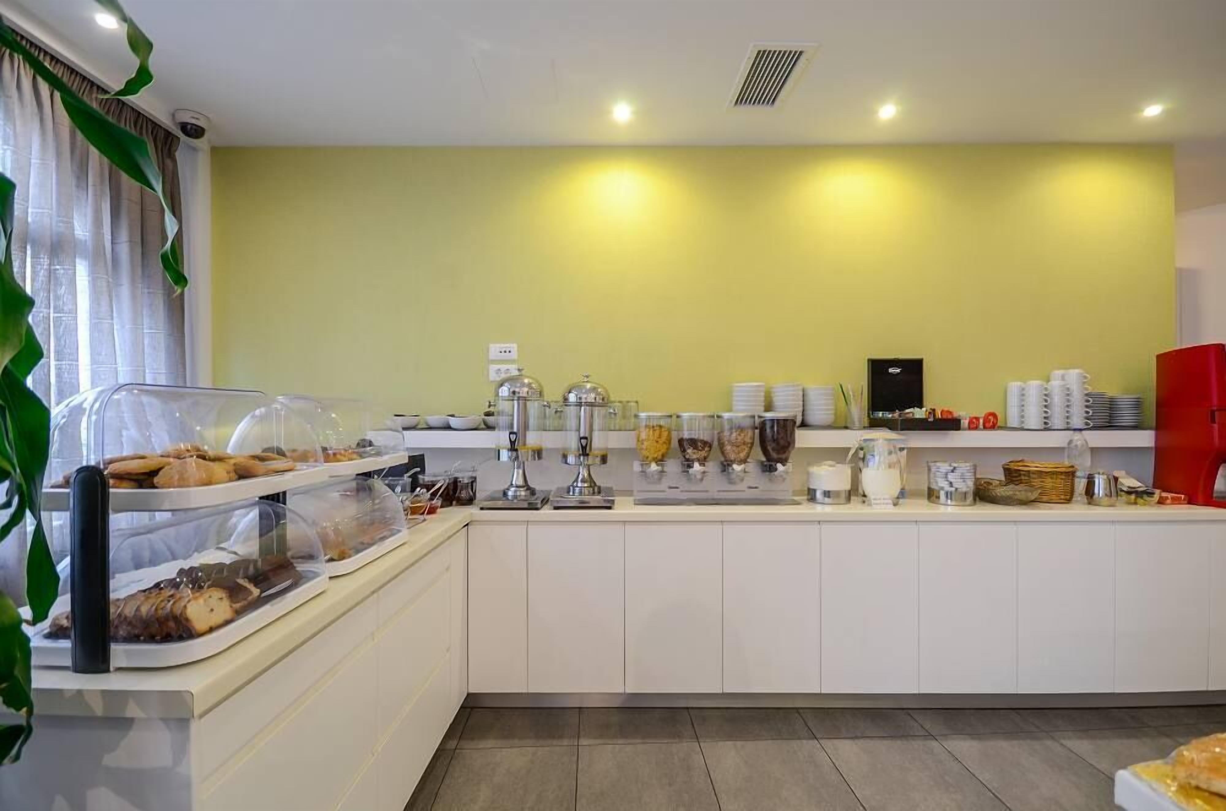 A buffet area with various food items and containers, a coffee machine, and a red refrigerator.