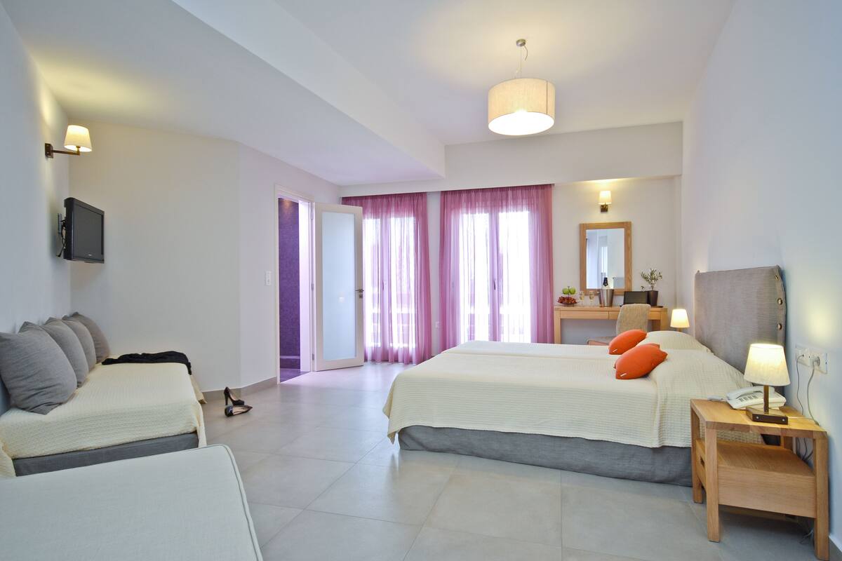 A modern hotel room with a large bed, a desk, a chair, and a television.