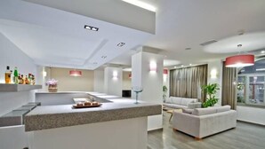 Una cocina moderna con una isla central, una zona de comedor con sofá y un amplio ventanal con cortinas.