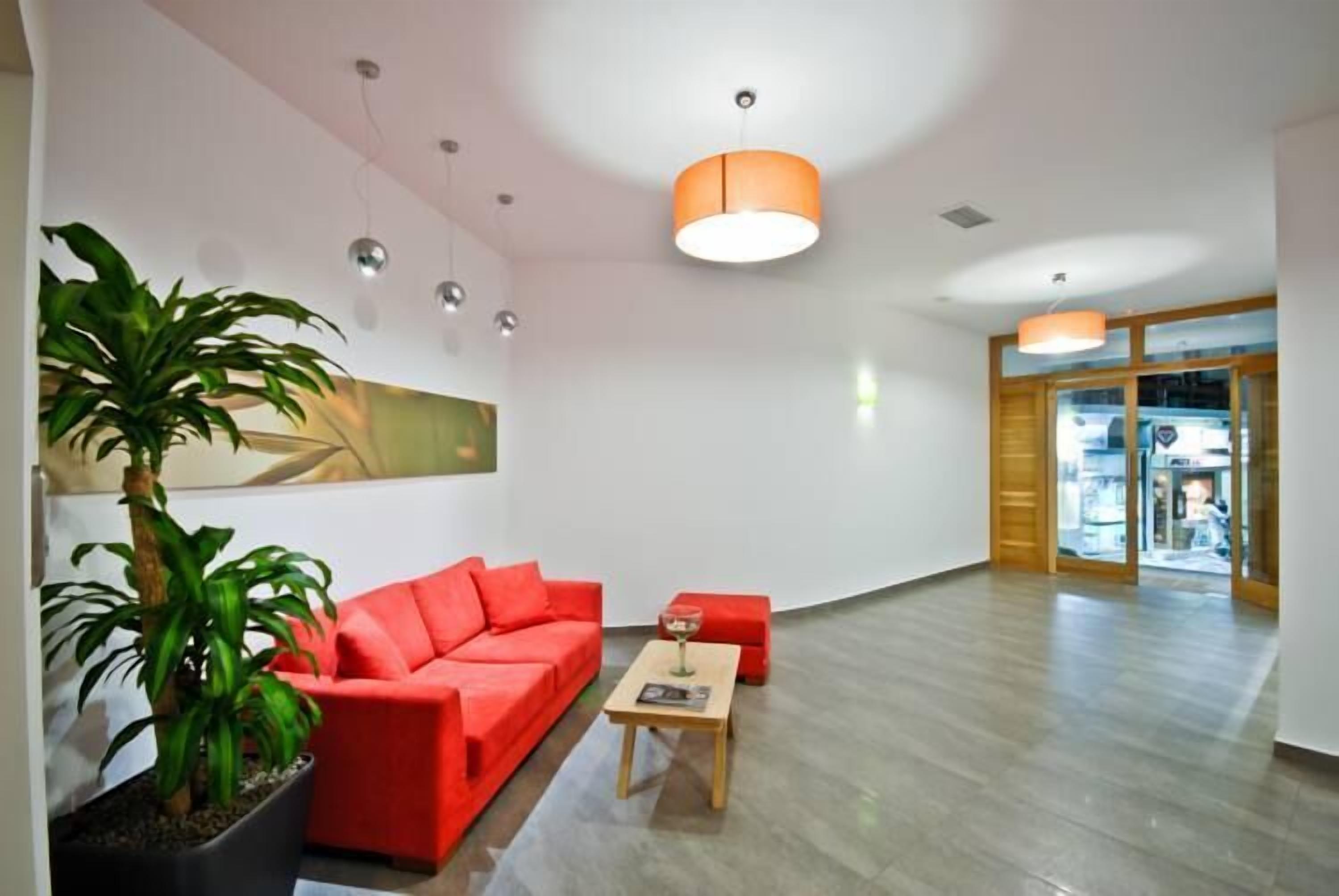A spacious lobby with a red sofa, a wooden coffee table, and a potted plant.