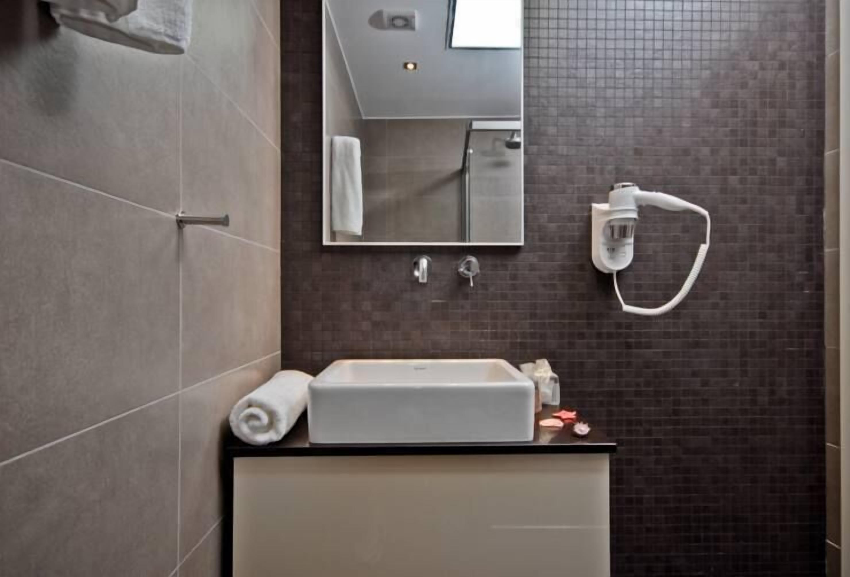 Un baño con lavamanos, espejo, toalla y ducha.