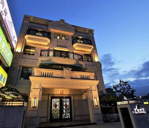 Un edificio de varios pisos con estilo arquitectónico clásico, que presenta una entrada central con un arco decorativo y un reloj encima.