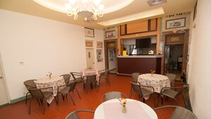 A dining area with round tables and chairs, a bar area, and a kitchen visible through an open doorway. - Mengqi Hostel (Huxi)