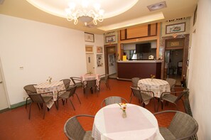 A dining area with round tables and chairs, a bar area, and a kitchen visible through an open doorway. - Mengqi Hostel (Huxi)
