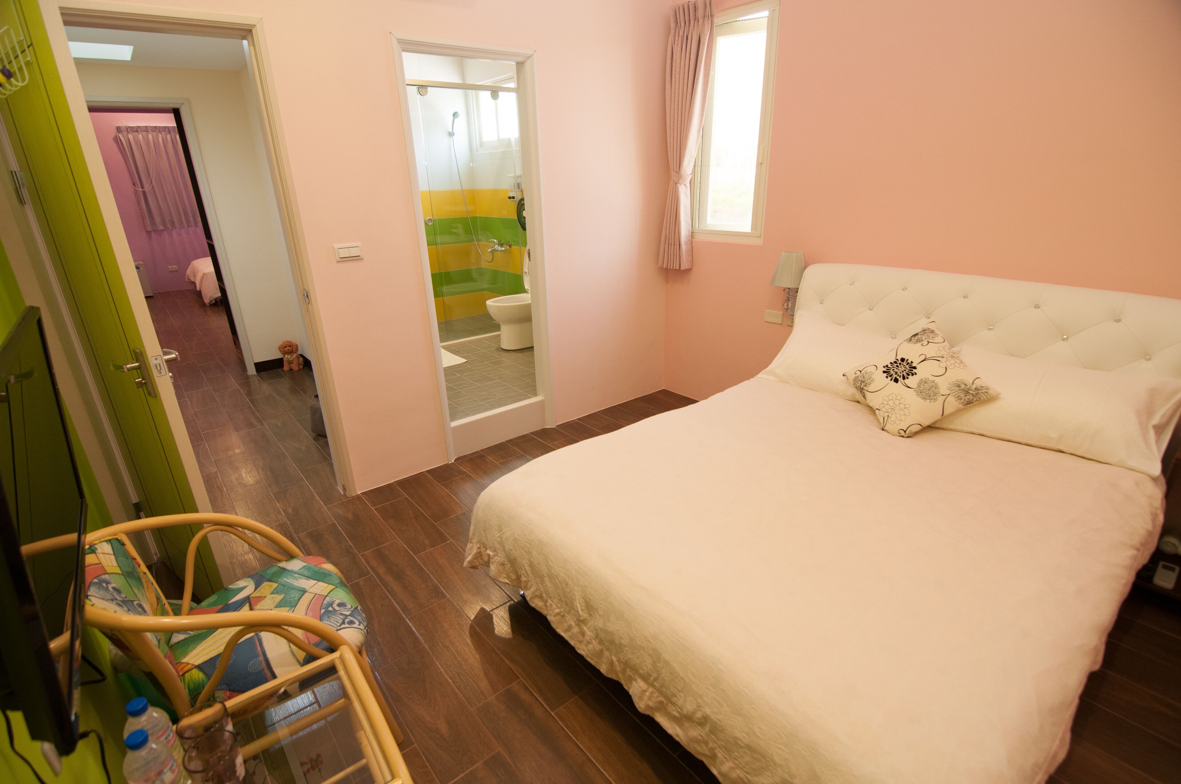 A bedroom with a bed, a chair, a window, and a bathroom visible through an open door.