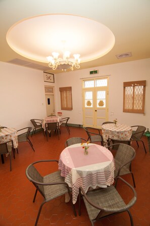 A dining area with round tables and chairs, a chandelier, and a door with glass panels. - Mengqi Hostel (Huxi)