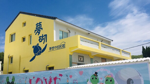 A yellow building with a turtle logo and Chinese characters. - Mengqi Hostel (Huxi)