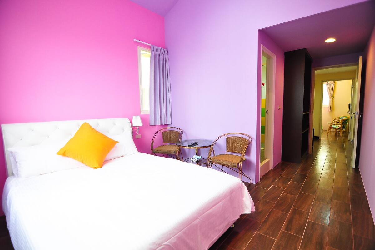 A room with a bed, two chairs, a small table, and a window with curtains.