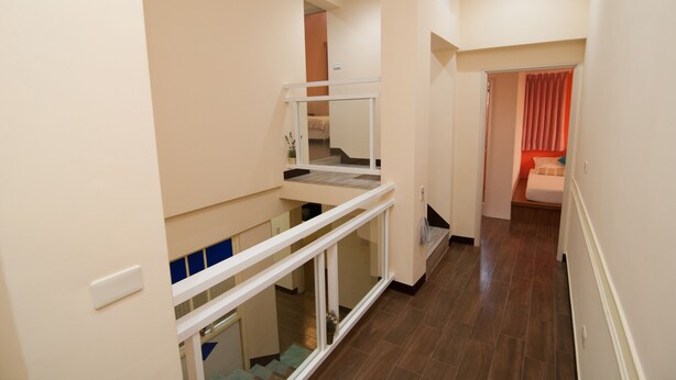 A multi-level interior with a staircase, a balcony, and a bedroom with a red curtain.