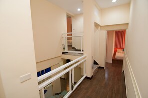 A multi-level interior with a staircase, a balcony, and a bedroom with a red curtain. - Mengqi Hostel (Huxi)