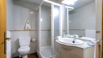 Un baño con inodoro, cabina de ducha y lavabo con espejo.