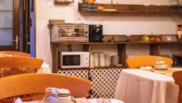 A restaurant interior with wooden furniture, tables set with white tablecloths, and a coffee sign on the wall.