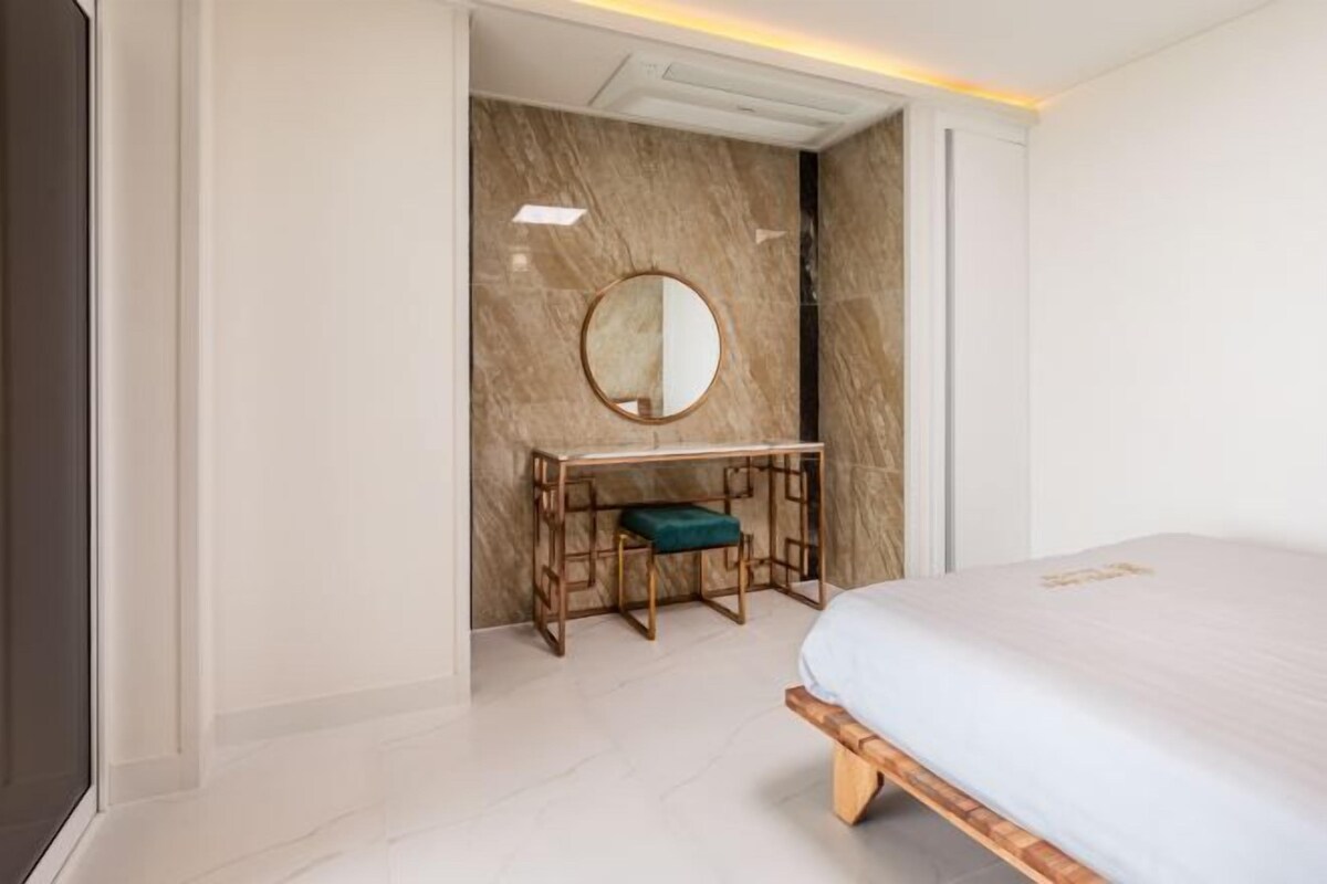 Une chambre à coucher moderne avec un lit, un bureau et une chaise, ainsi qu’un miroir au mur.