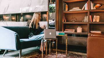 A modern living room with a sofa, a small table with a laptop, a bookshelf, and a decorative rug.