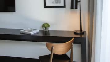 Un escritorio moderno con una silla, un cuadro en la pared y una lámpara de pie.